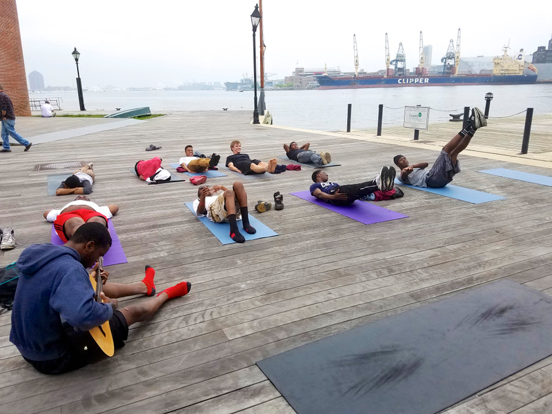 Students with the Black Male Yoga Initiative practice on a pier